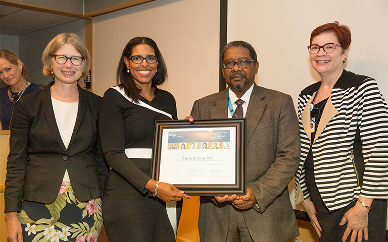 four faculty posing with award certificate