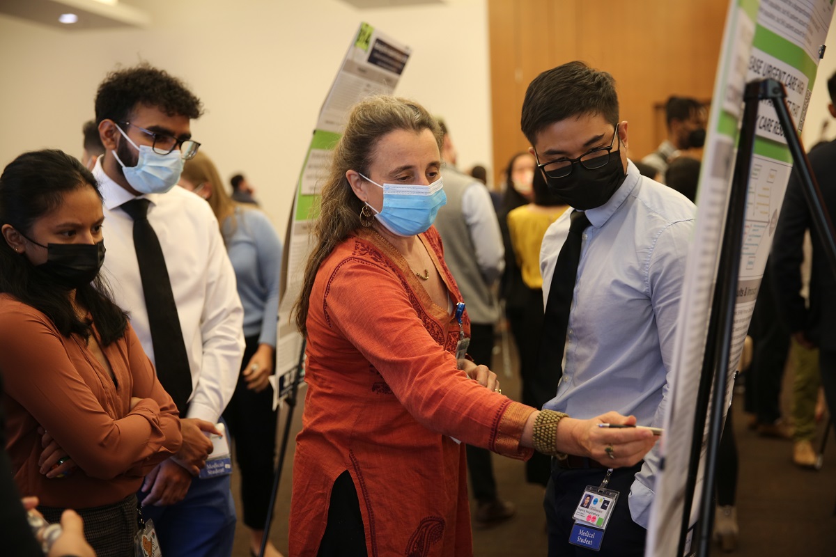 MS2 Alyssa Rivera, MS2 Amritpal Singh, and Sara Newmann, MD, MPH, in conversation with MS2 Bagieng Keophimphone, during the poster session at the UCSF School of Medicine Clinical Microsystems Clerkship Health Systems Improvement Symposium.