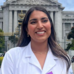 Person wearing a white coat in front of a building