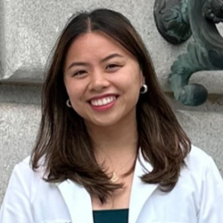 Person wearing a white coat in front of a building