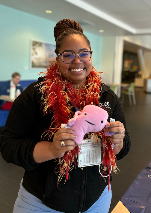 a person smiling and holding an axolotl stuffie