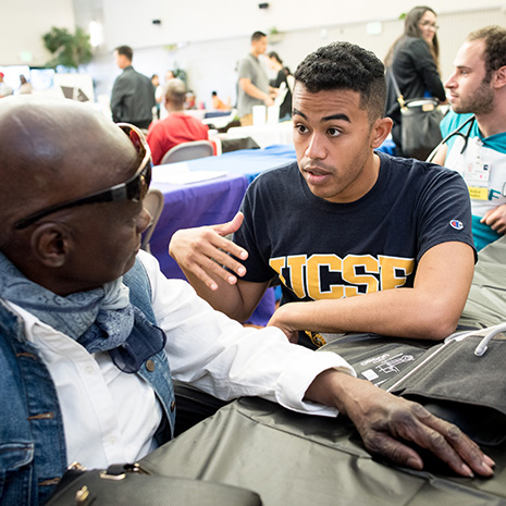 Medical students do blood pressure checks and and dental students do screenings with community members at the Southeast Community Health Fair.  Med student Dereck Paul talks to participant Mary Crenshaw before her blood pressure screening.