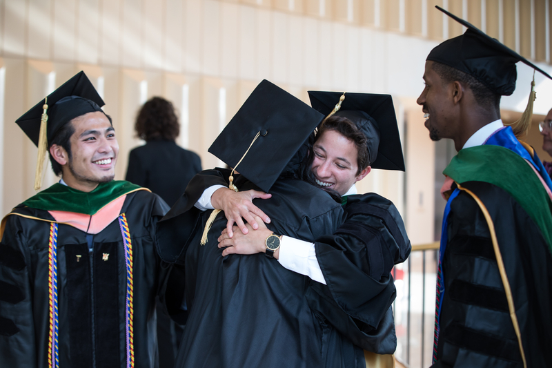 students at graduation hugging and smiling